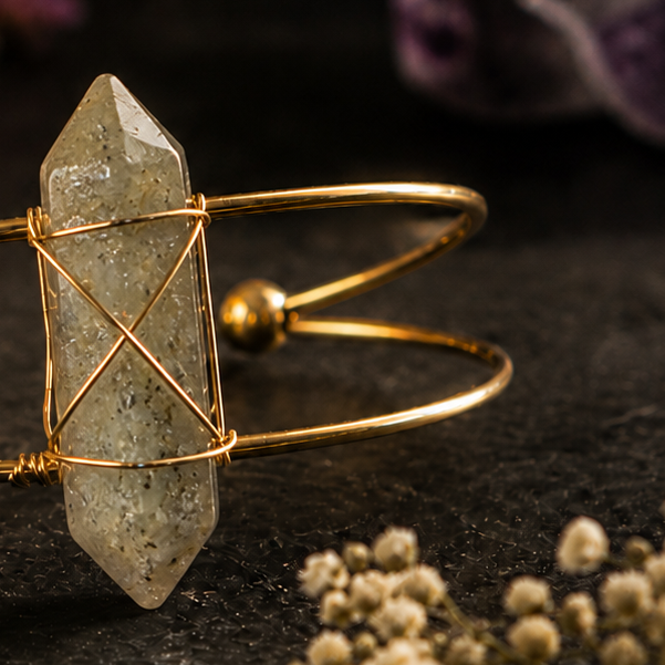 Close-up van labradoriet edelsteen armband met goudkleurige details en natuurlijke grijsgroene steen