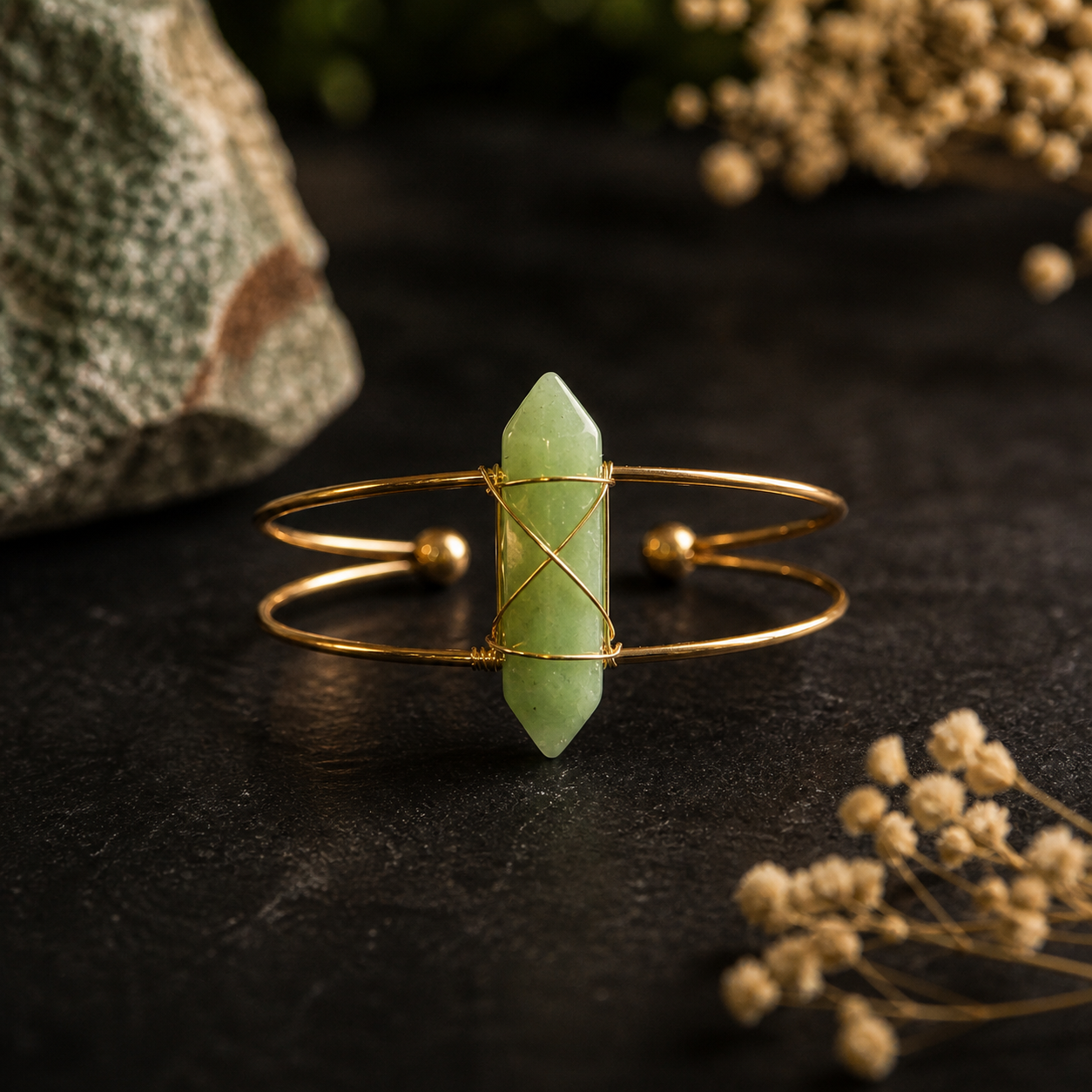 Aventurijn armband gouden cuff met groene edelsteen op donkere achtergrond
