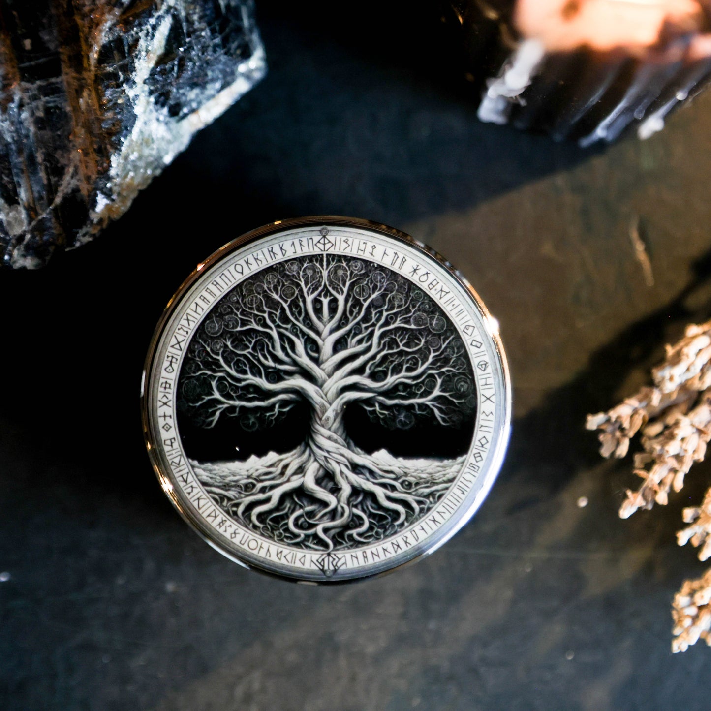 Close-up van kruiden grinder met Levensboom ontwerp, spirituele runen en glanzend metalen afwerking op donkere achtergrond.