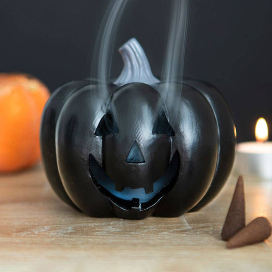 Detail van zwarte Jack-O’-Lantern met uitgesneden grijns – decoratieve wierookhouder voor Halloween of gothic interieur.